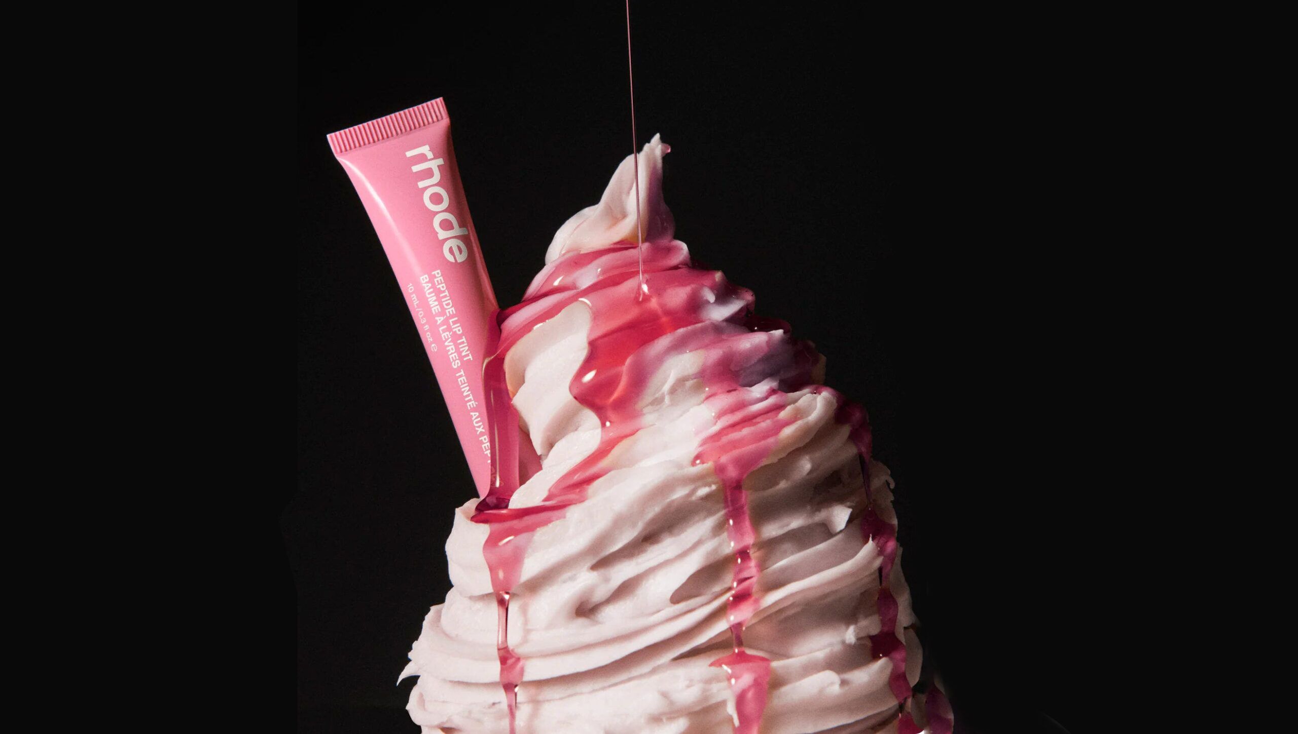 Ice cream with strawberry syrip on it and a rhode lipstick planted in it like you would a flake